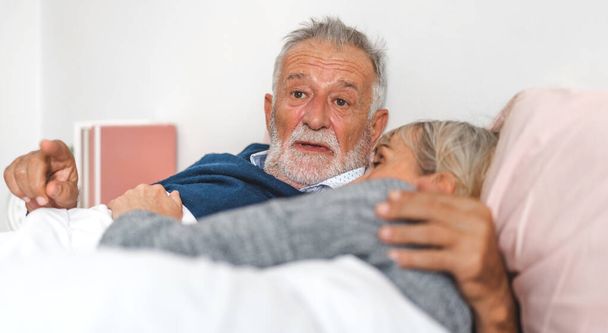 Senior ευτυχισμένο ζευγάρι χαλαρωτικό και μιλάμε μαζί ξαπλωμένοι στο κρεβάτι στην κρεβατοκάμαρα στο σπίτι. - Φωτογραφία, εικόνα