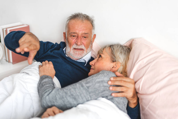 Starsza szczęśliwa para relaks i rozmowy razem leżące na łóżku w domu w sypialni.Emerytura para koncepcja - Zdjęcie, obraz