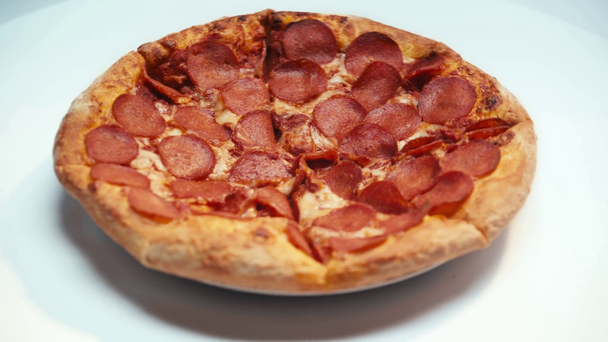 Selective focus of spinning pizza with pepperoni on white background - Felvétel, videó