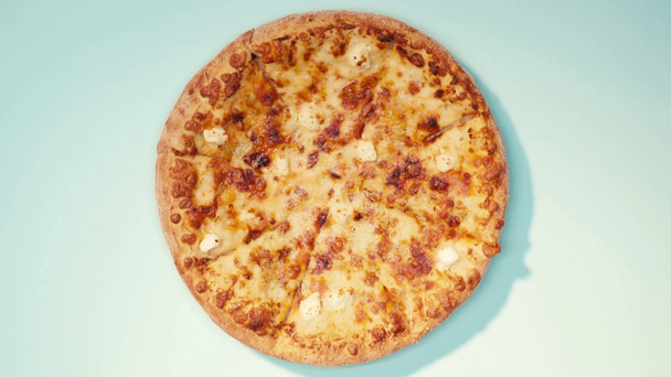 Vista dall'alto di deliziosa pizza con formaggio su sfondo blu - Filmati, video