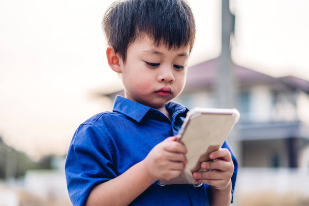 Portrait of cute little asian boy relaxing using digital smartphone.Young asian children looking at screen typing message and playing game online or social media  - Fotó, kép