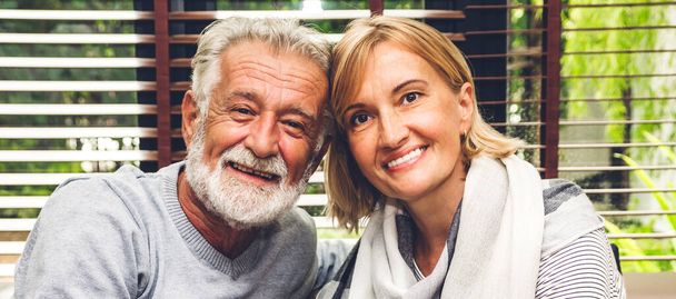 Portrait of smiling senior happy couple relaxing and talking together sit on sofa at home.Elderly husband and wife looking at camara.Retirement couple concept - Foto, imagen