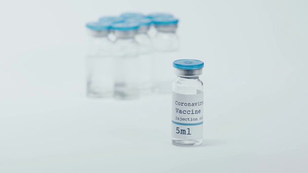 bottle with coronavirus vaccine near scientist in latex glove on white - Záběry, video