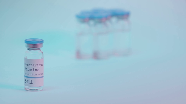 обрезанный вид человека, принимающего шприц возле бутылки с надписью вакцины на синем - Кадры, видео
