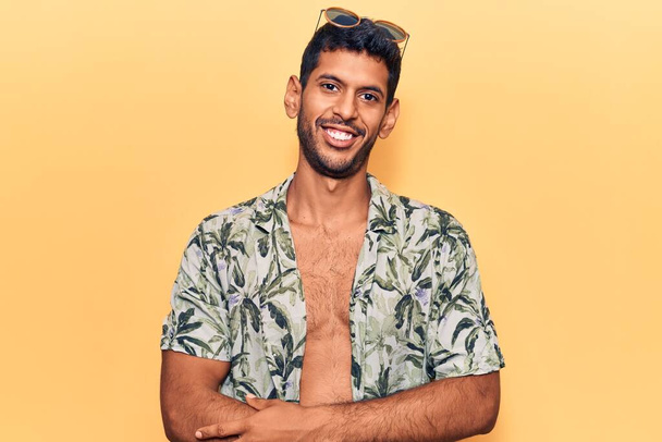 Young latin man wearing summer shirt and sunglasses happy face smiling with crossed arms looking at the camera. positive person.  - Foto, Bild