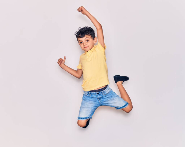 Suloinen lapsi päällään rento vaatteita hyppäämällä yli eristetty valkoinen tausta - Valokuva, kuva