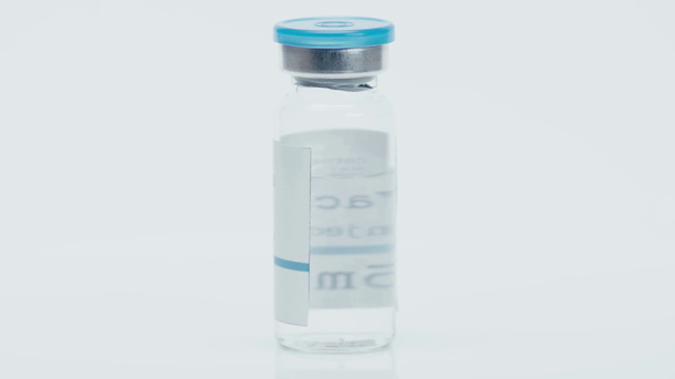 Бутылка с коронавирусной вакциной с надписью на белом  - Кадры, видео