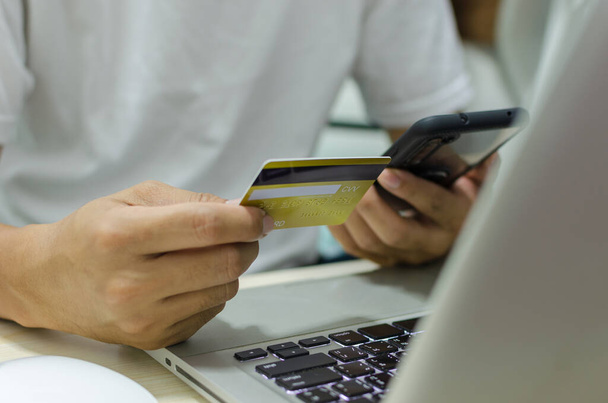 Homem compras on-line usando laptop com cartão de crédito. Mãos segurando cartão de crédito e smartphone. - Foto, Imagem