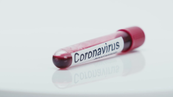селективный фокус пробирки с коронавирусной надписью, вращающейся на белом - Кадры, видео