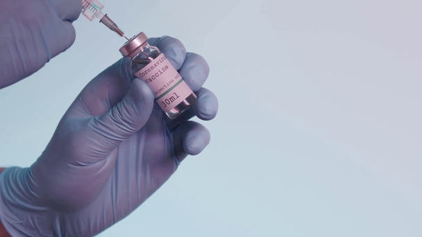 partial view of person holding syringe and bottle with vaccine isolated on grey - Séquence, vidéo