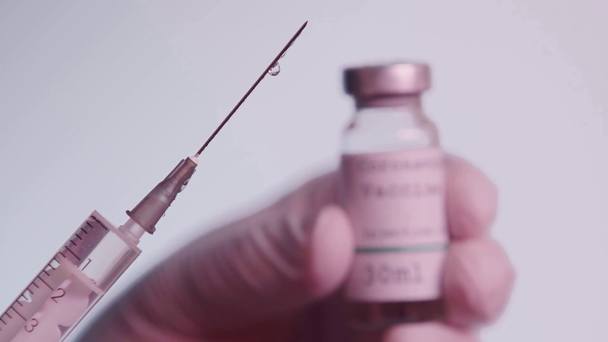 częściowy widok naukowca trzymającego strzykawkę ze szczepionkowym płynem wyizolowanym na szaro - Materiał filmowy, wideo
