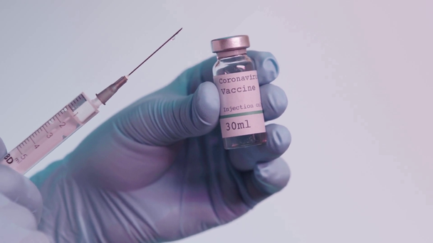 rack focus of person holding bottle with vaccine and syringe isolated on grey - Záběry, video