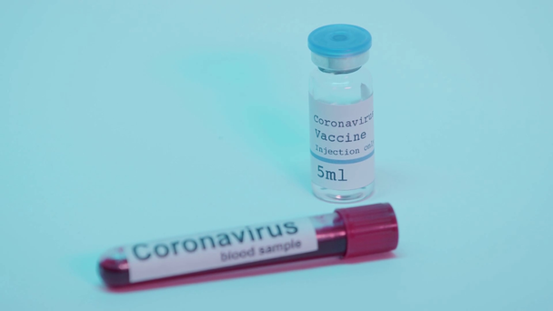 focus pull of blood sample and bottle with coronavirus vaccine on blue - Filmagem, Vídeo