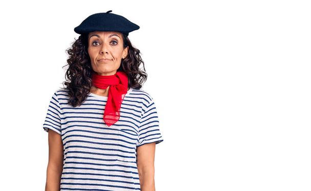 Schöne Frau mittleren Alters mit französischer Baskenmütze und Schal mit ernstem Gesichtsausdruck. einfacher und natürlicher Blick auf die Kamera.  - Foto, Bild