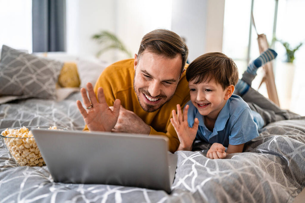 Happy father and son are talking via video link with relatives or teacher - Φωτογραφία, εικόνα
