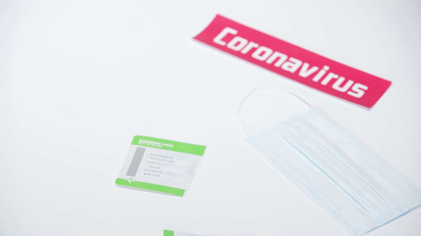 Mężczyzna w lateksowych rękawiczkach rozrywa kartę pokładową w pobliżu maski medycznej na białym  - Materiał filmowy, wideo
