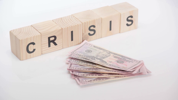 Person throwing dollars near cubes with crisis lettering on white background - Footage, Video