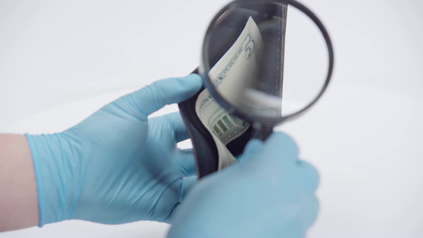 Man holding magnifying glass near wallet with dollar on white background - Footage, Video