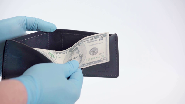 Hombre en guantes de látex mostrando dólar en cartera sobre fondo blanco - Imágenes, Vídeo