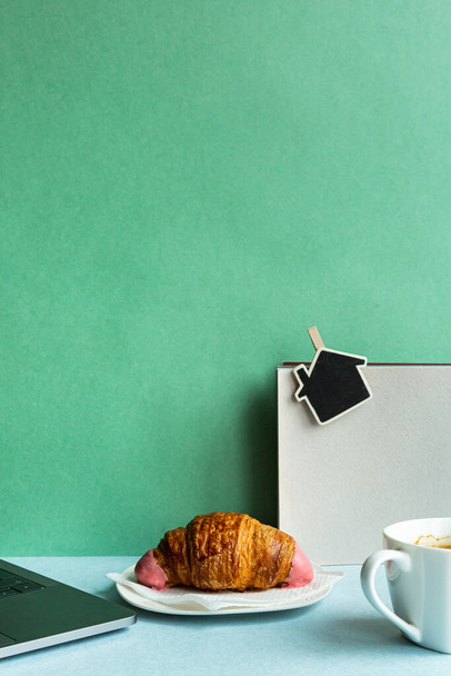 Reggeli munkahelyi laptop kávé croissant fénymásoló. Üzleti koncepció pasztell színekben. - Fotó, kép