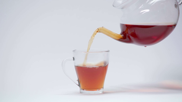 Verter el té negro de la tetera en una taza sobre blanco - Imágenes, Vídeo