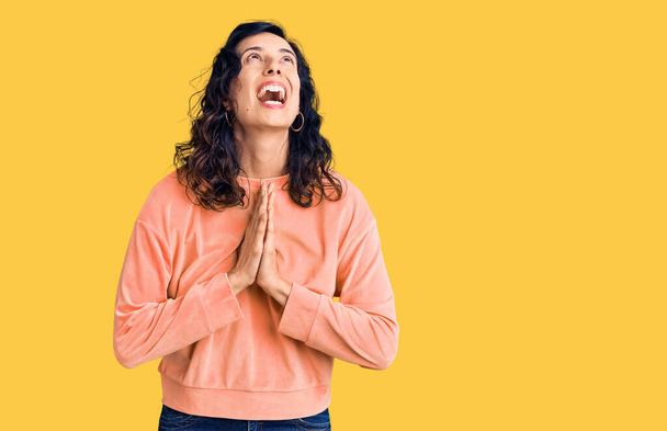 Jonge mooie Latijns-Amerikaanse vrouw draagt casual kleding bedelen en bidden met de handen samen met hoop uitdrukking op het gezicht zeer emotioneel en bezorgd. bedelen.  - Foto, afbeelding