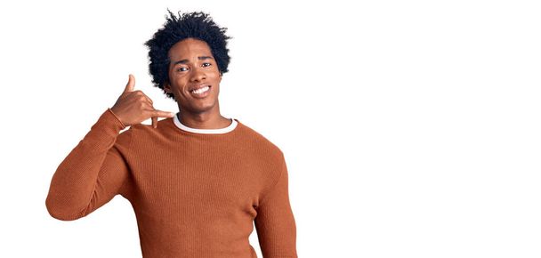 Handsome african american man with afro hair wearing casual clothes smiling doing phone gesture with hand and fingers like talking on the telephone. communicating concepts.  - Фото, изображение