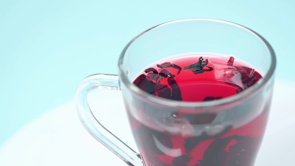 tè con foglie secche in tazza su azzurro - Filmati, video