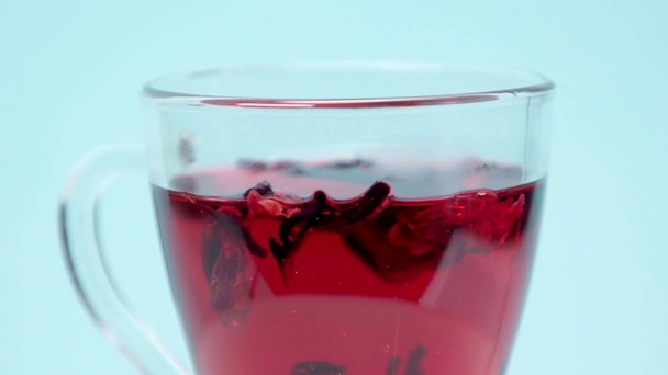  Чашка чаю гібіскуса, що кружляє навколо ізольовано на синьому
 - Кадри, відео