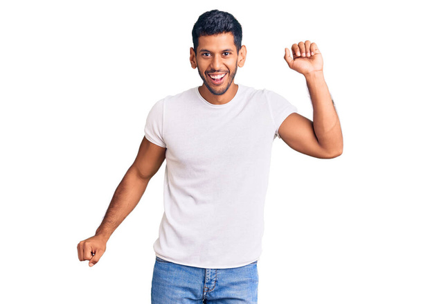 Young latin man wearing casual clothes dancing happy and cheerful, smiling moving casual and confident listening to music  - Photo, Image