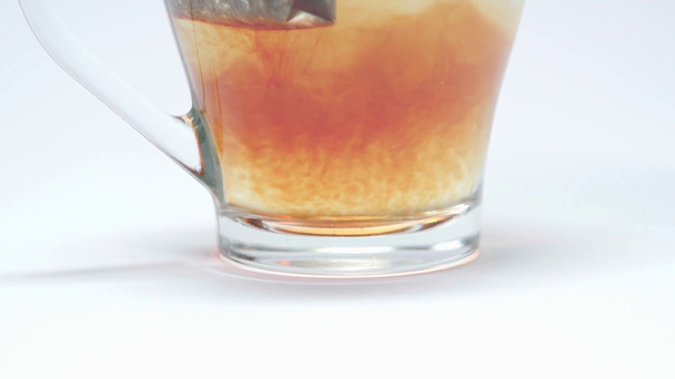 Vue rapprochée du sachet de thé à infuser en tasse sur fond blanc - Séquence, vidéo