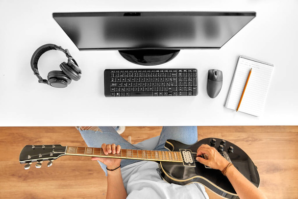 young man with computer playing guitar at table - Photo, image
