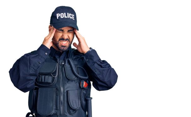 Young hispanic man wearing police uniform with hand on head, headache because stress. suffering migraine.  - Fotoğraf, Görsel