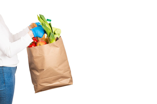 Food delivery or shopping concept. Grocery store shopping. Woman holds a paper bag filled with groceries such as fruits, vegetables, milk, yogurt, eggs isolated on white. Banner with copy space - Photo, Image