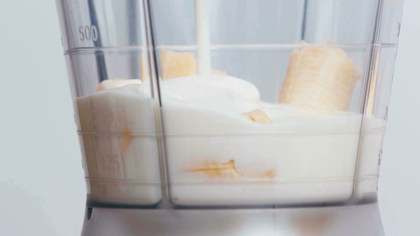 Zbliżenie mleka wlewającego się do blendera z bananami - Materiał filmowy, wideo
