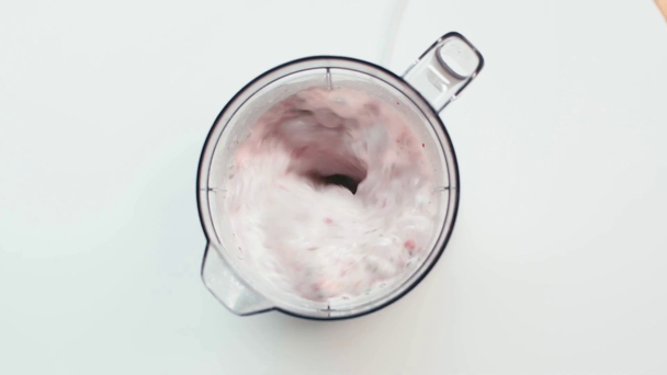 Vista superior del hombre mezclando fresas y menta con leche en licuadora sobre blanco - Imágenes, Vídeo