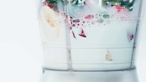 Primer plano de la leche vertiendo en la licuadora con frutas aisladas en blanco - Imágenes, Vídeo