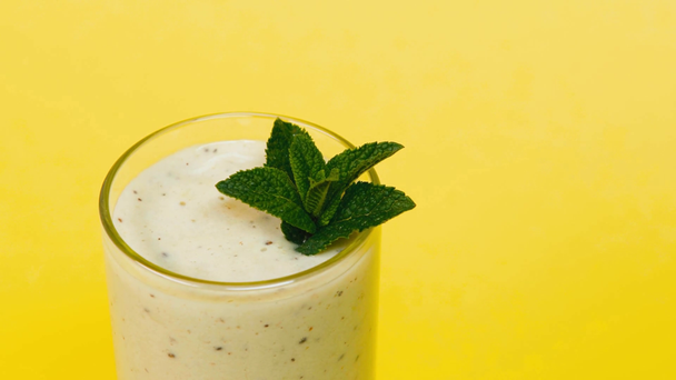cropped view of man adding fresh mint in prepared smoothie isolated on yellow - Footage, Video