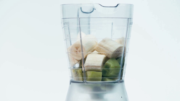 krájené banány pádu v moderním mixéru s kiwi izolované na bílém - Záběry, video