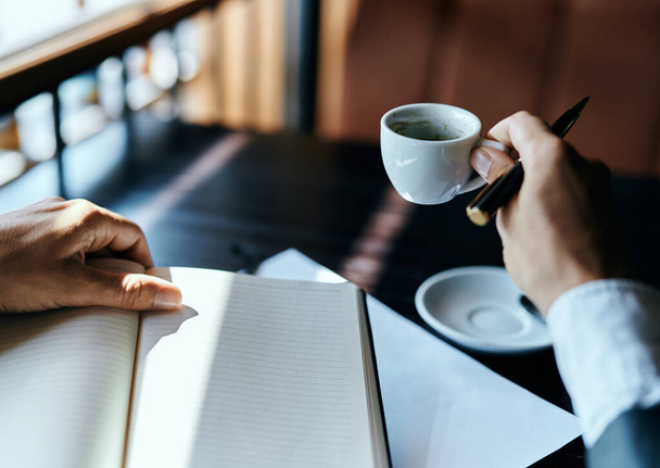 üzletasszony egy kávézóban egy könyvvel az asztalon dokumentumok egy csésze kávé munka életmód - Fotó, kép