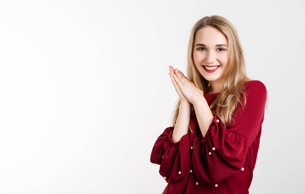 Surprised girl with long blonde hair keeps hands together near chin, smiles gently, has cute expression. Positive human emotions, reaction and astonishment. Copy space for your text - Photo, Image