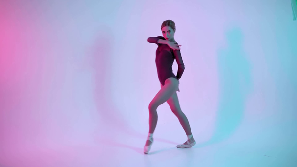 Joven bailarina realizando movimientos de baile sobre fondo azul y rosa - Imágenes, Vídeo