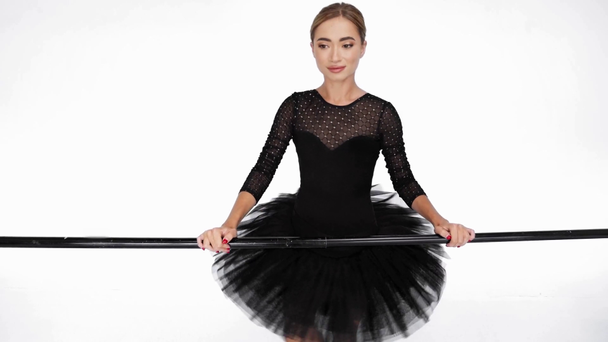 Elegante bailarina practicando ballet clásico se mueve en barra sobre fondo blanco - Metraje, vídeo