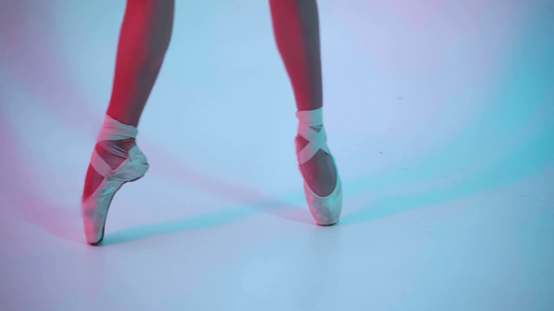 Обрізаний вид балерини, що виконує балетні ходи на синьо-рожевому фоні
 - Кадри, відео