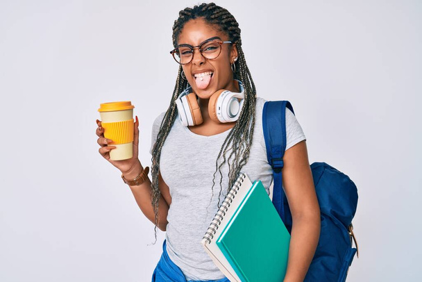 Fiatal afro-amerikai nő fonat visel diák hátizsák ivás kávé kilóg nyelv boldog vicces kifejezés.  - Fotó, kép
