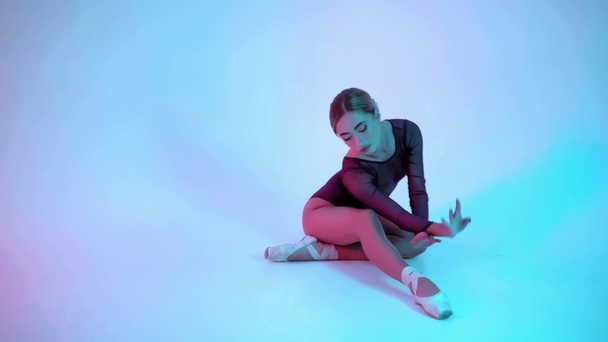 Bailarina elegante realizando movimientos de ballet clásico sobre fondo azul y rosa - Metraje, vídeo