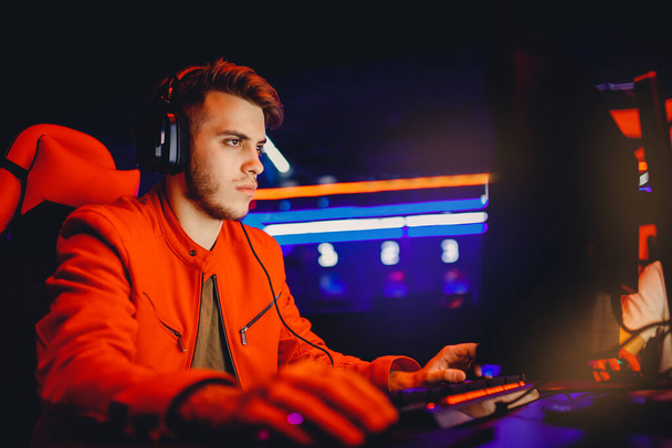 Профессиональный игрок, играющий в турниры онлайн компьютерные игры с наушниками, красный и синий - Фото, изображение