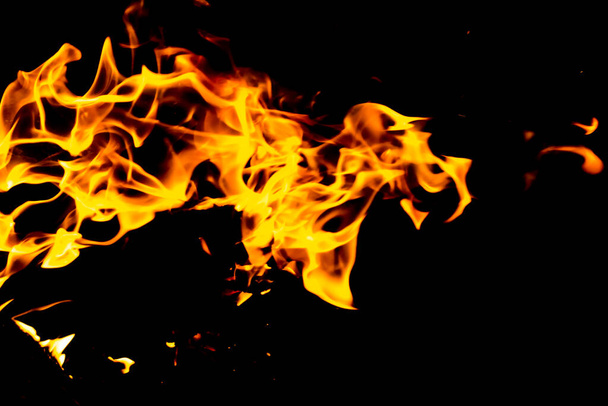 Vuurtongen van rode vlam op een zwarte achtergrond. Vuurvlam in de nacht - Foto, afbeelding