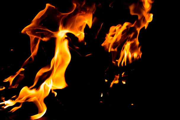 Vörös láng tüzes nyelve fekete háttérrel. Tűzláng az éjszakában - Fotó, kép