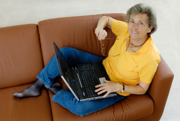 Senior woman with laptop on a couch - Photo, Image